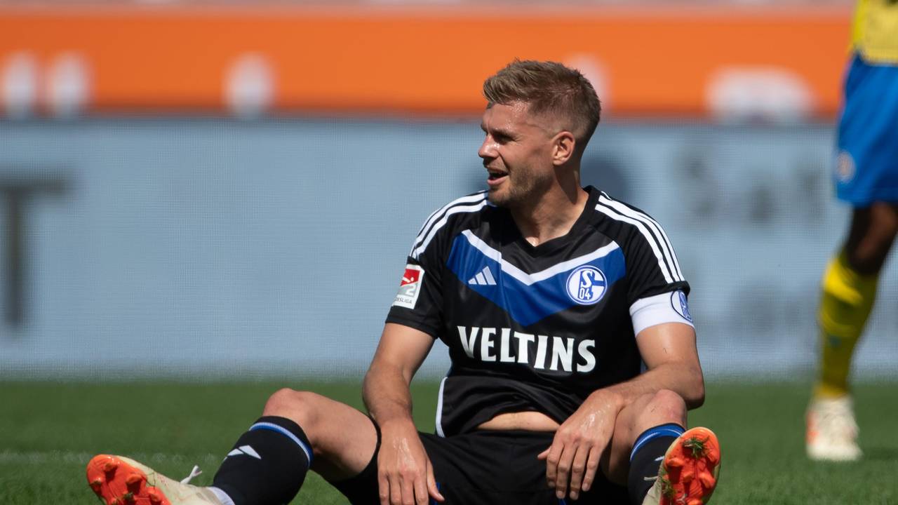 Simon Terodde sitzt im Schalke-Trikot auf dem Rasen.