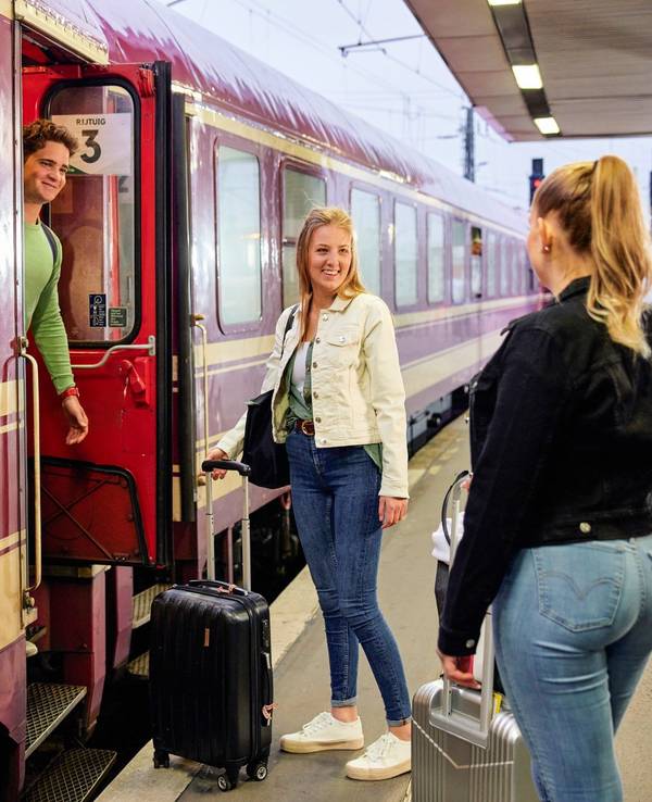 Drei Personen an einem Bahnsteig.