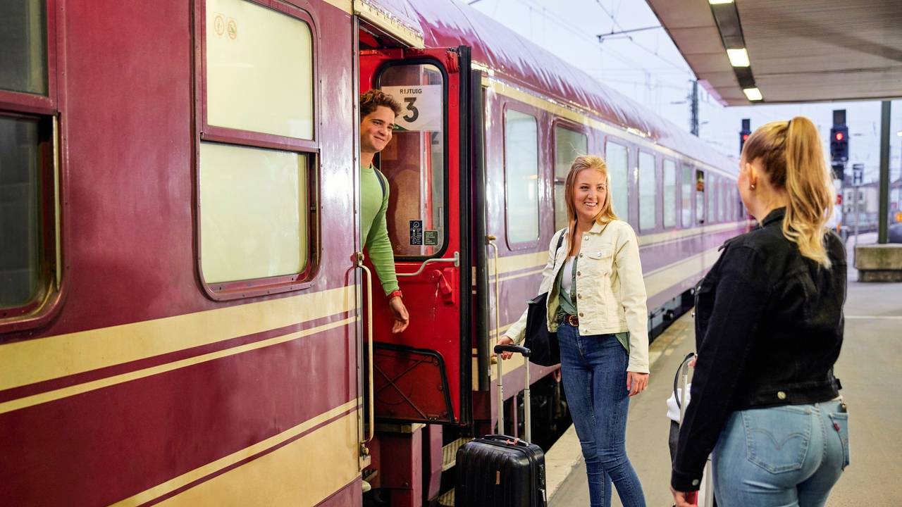 Drei Personen an einem Bahnsteig.