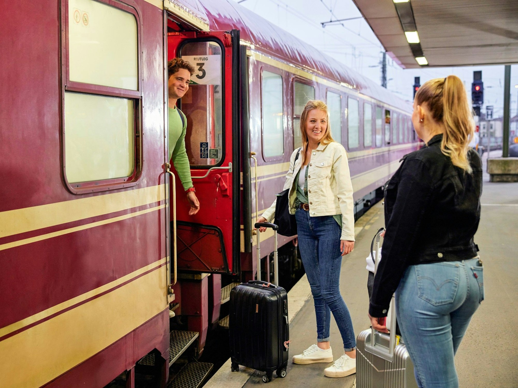 Drei Personen an einem Bahnsteig.
