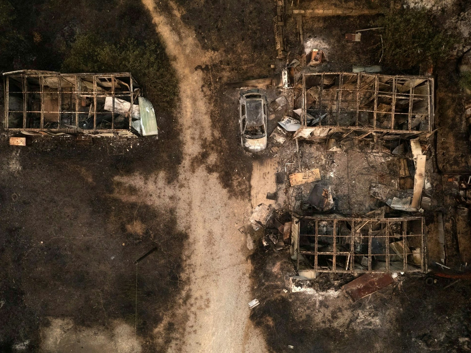 Nach einem Waldbrand sind im griechischen Palagia ein verbranntes Auto und ausgebrannte Lagerhäuser zu sehen. Bei den Waldbränden im Nationalpark Dadia in Nordostgriechenland sind am Dienstag die verbrannten Leichen von 18 Menschen gefunden worden.
