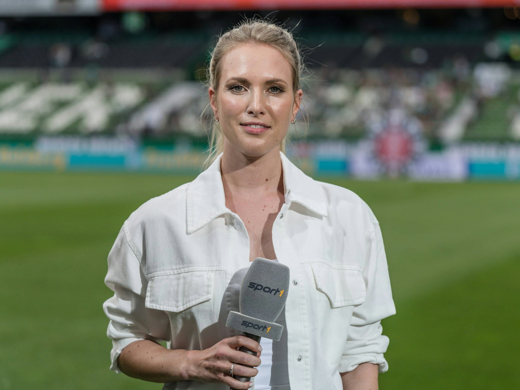 Ruth Hofmann steht im Stadion und hält ein Sport1-Mikrofon in der Hand.