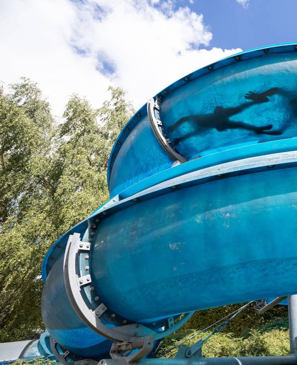 Zwei Personen rutschen eine Wasserrutsche runter.