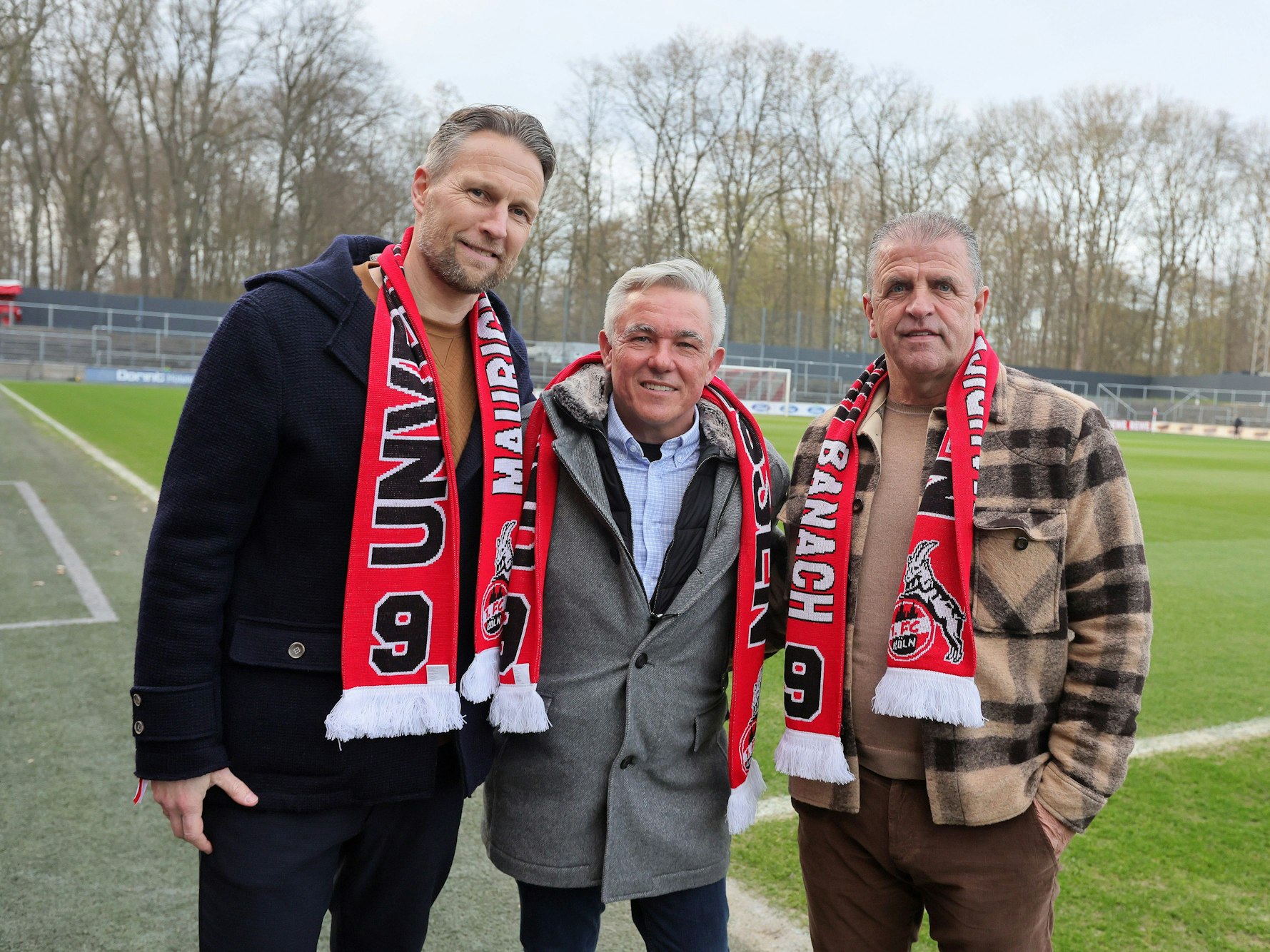 Alexander Bade, Olaf Janßen und Franz Wunderlich zu Gast posieren und tragen Schals mit der Aufschrift: „Unvergessen – Maurice Banach“.