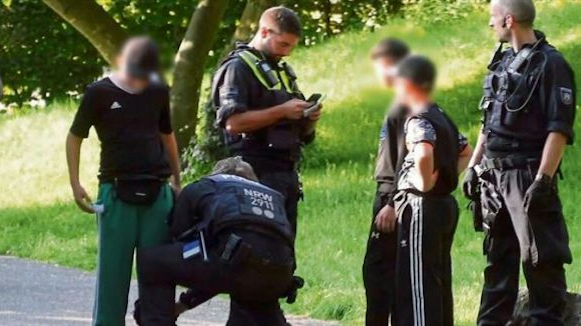 Polizisten durchsuchen drei Kinder von Kopf bis Fuß im Mülheimer Stadtpark-