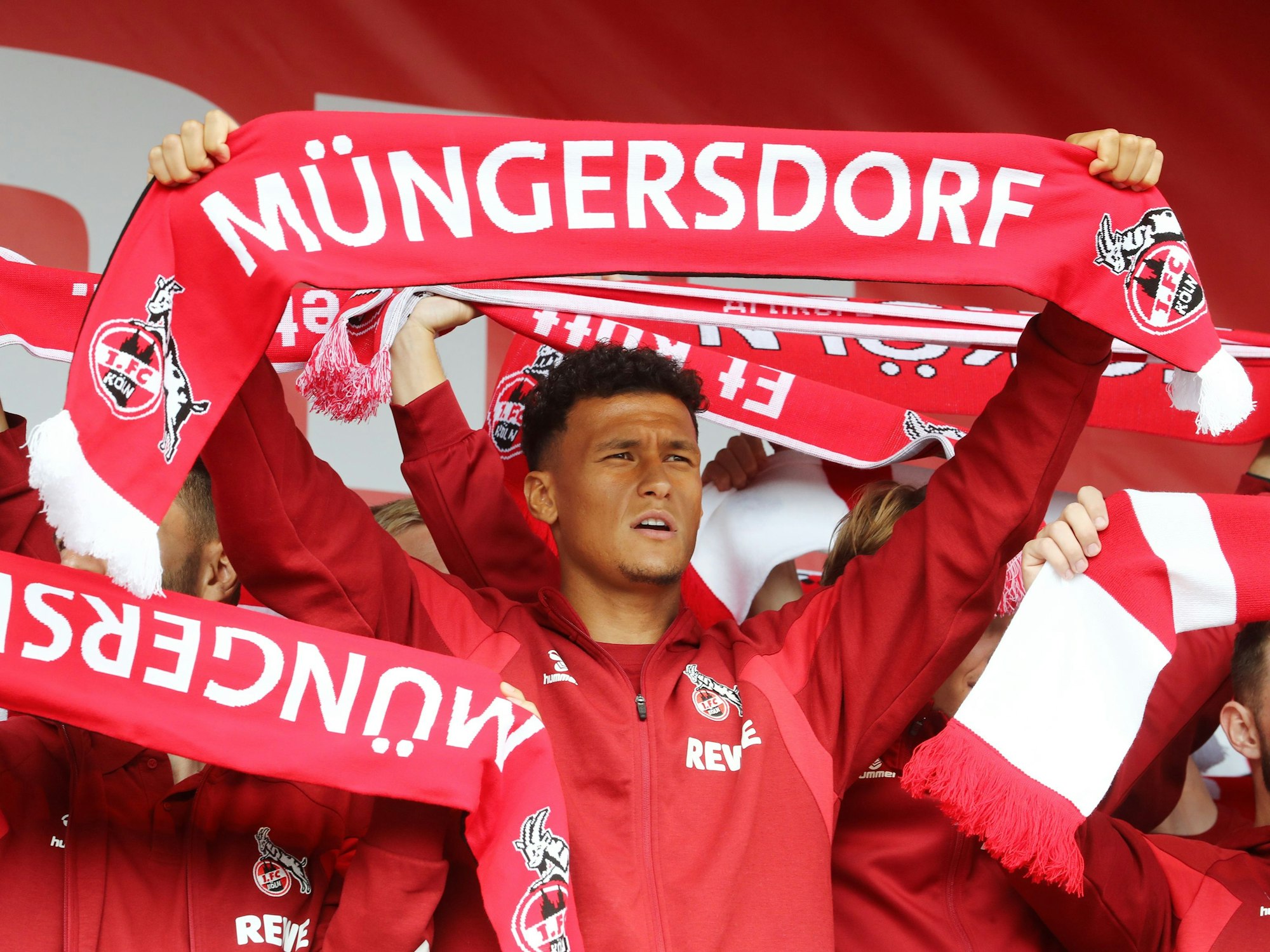 Davie Selke hält einen FC-Schal mit der Aufschrift „Müngersdorf“ hoch.