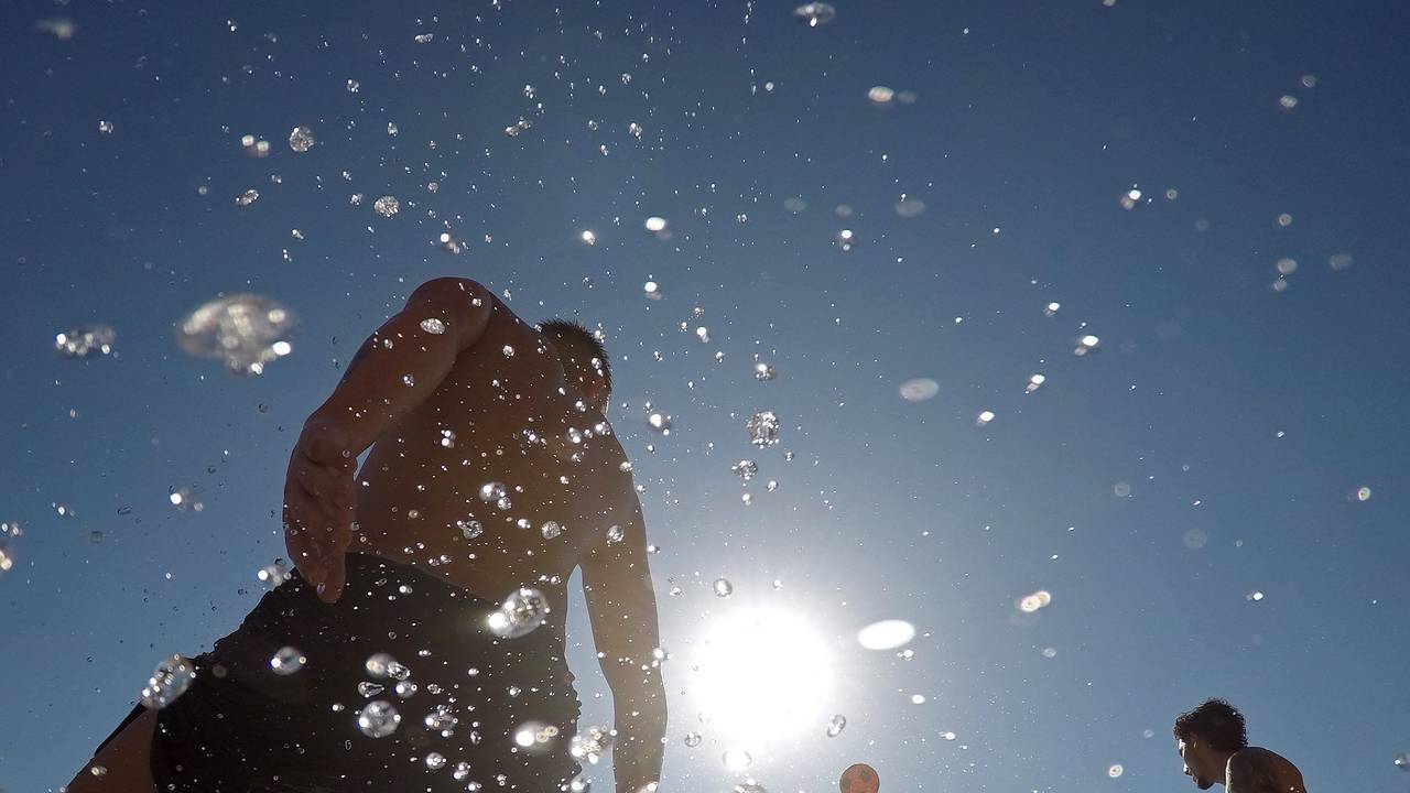 Menschen spielen mit einem Ball am Meer an einem warmen Sommertag am Strand Cala Major auf Mallorca.