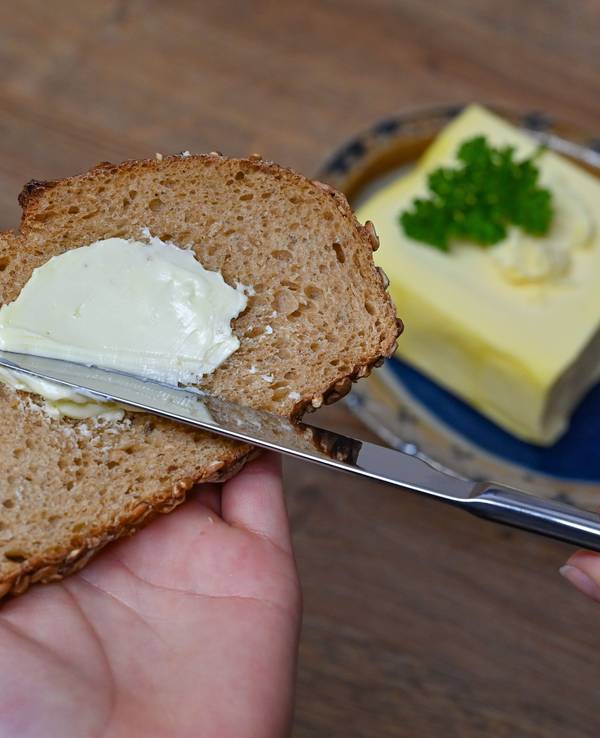 Eine Person streicht Butter auf eine Scheibe Brot. Symbolbild für Brot-Rückruf.