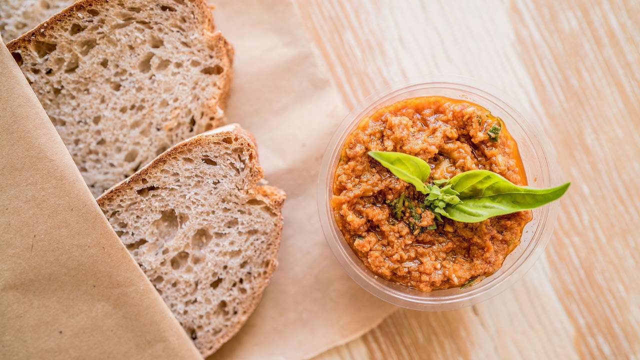 Das Bild zeigt zwei Brotschreiben und eine Schale mit roter Pesto-Sauce.