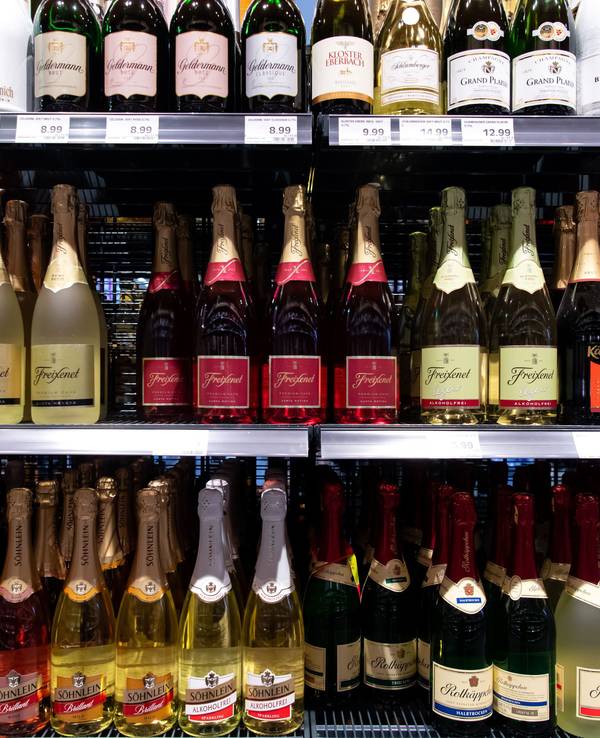 Sektflaschen von verschiedenen Herstellern stehen in einem Supermarktregal.