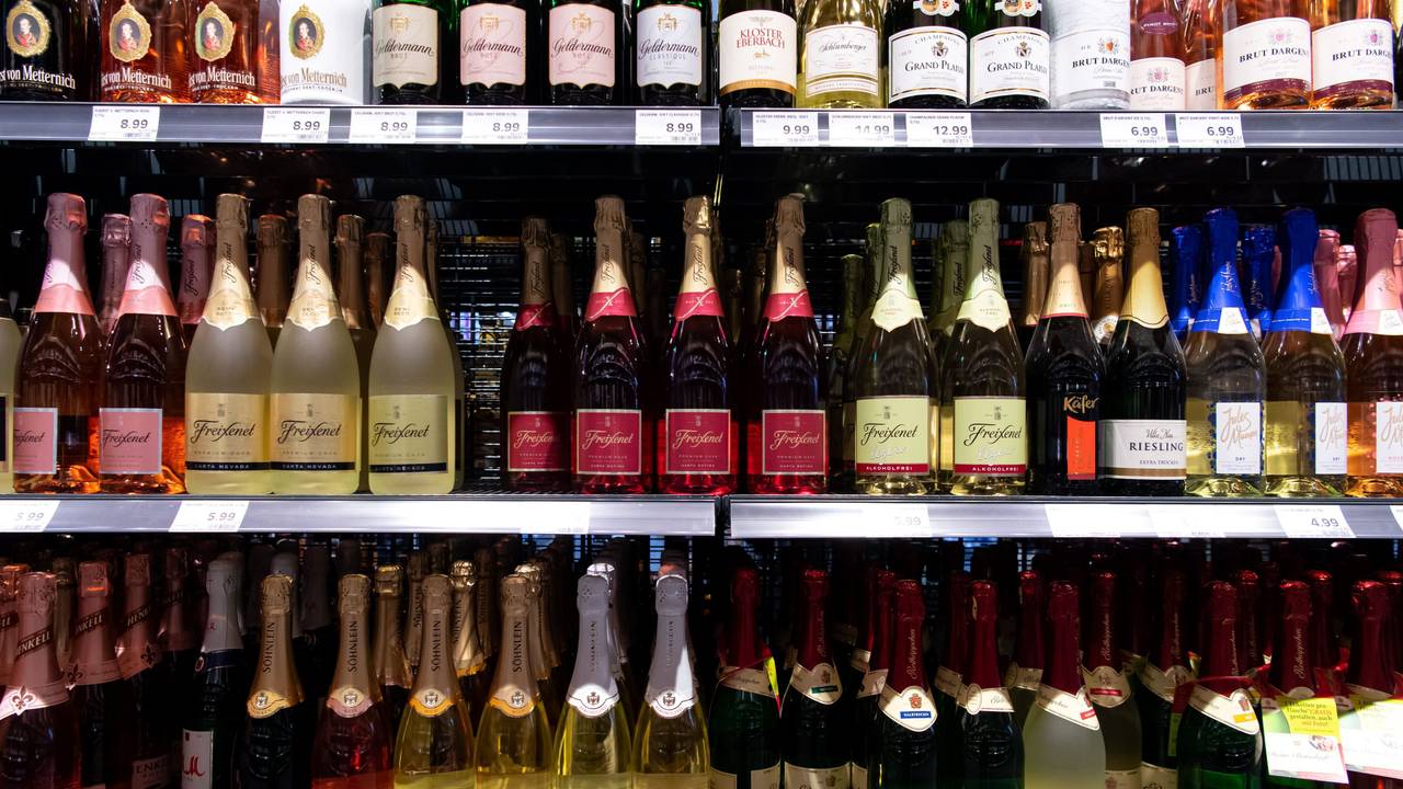Sektflaschen von verschiedenen Herstellern stehen in einem Supermarktregal.