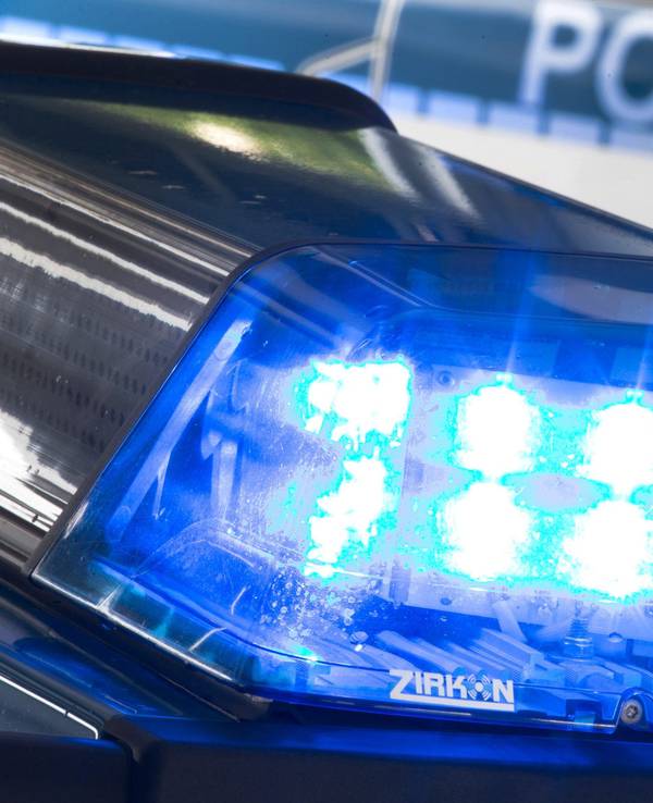 Ein Blaulicht leuchtet auf dem Dach eines Polizeiwagens. Im Hintergrund steht ein weiterer Streifenwagen.