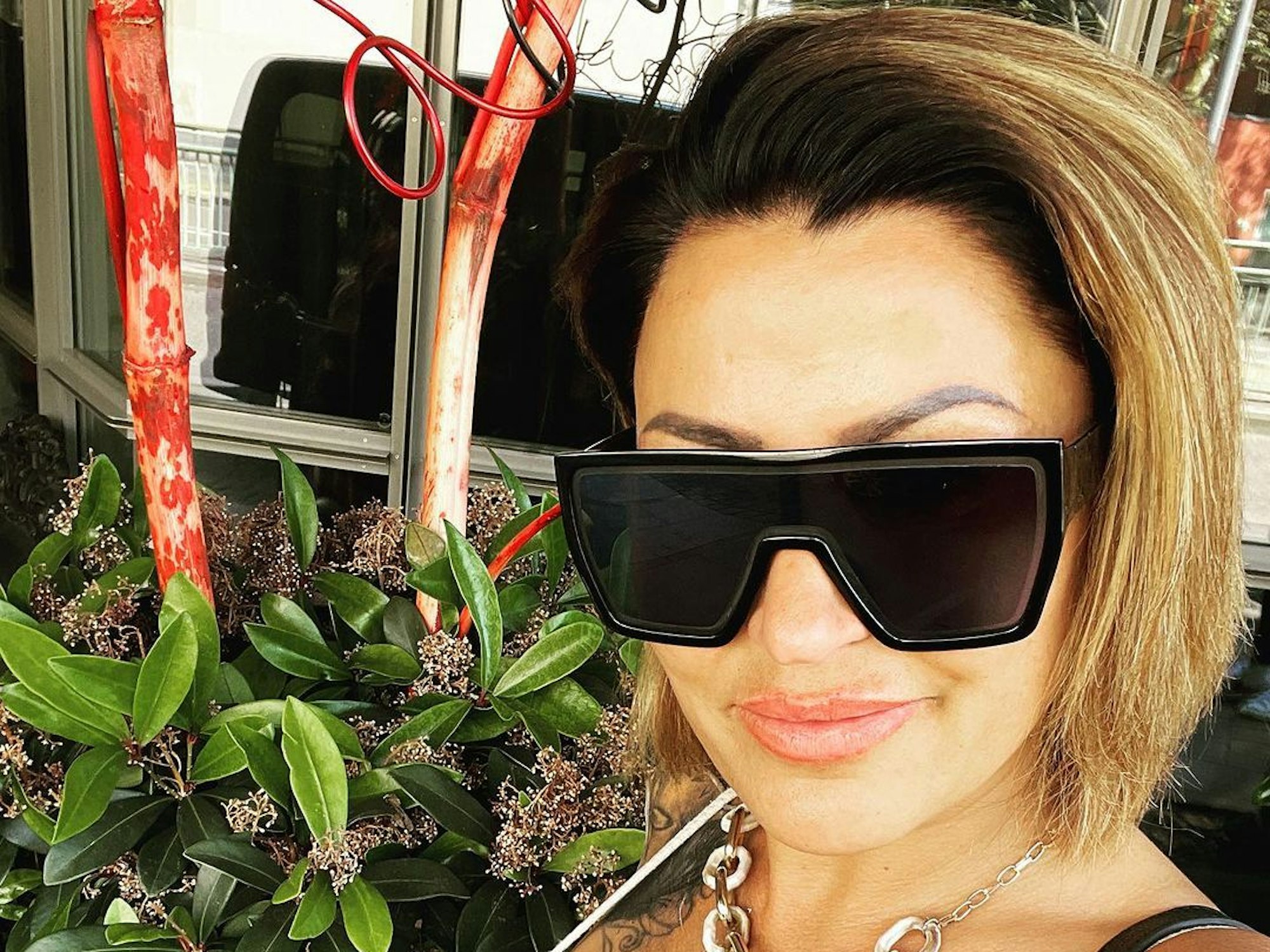 Jasmin Herren trägt ein weißes Oberteil und eine schwarze Sonnenbrille.