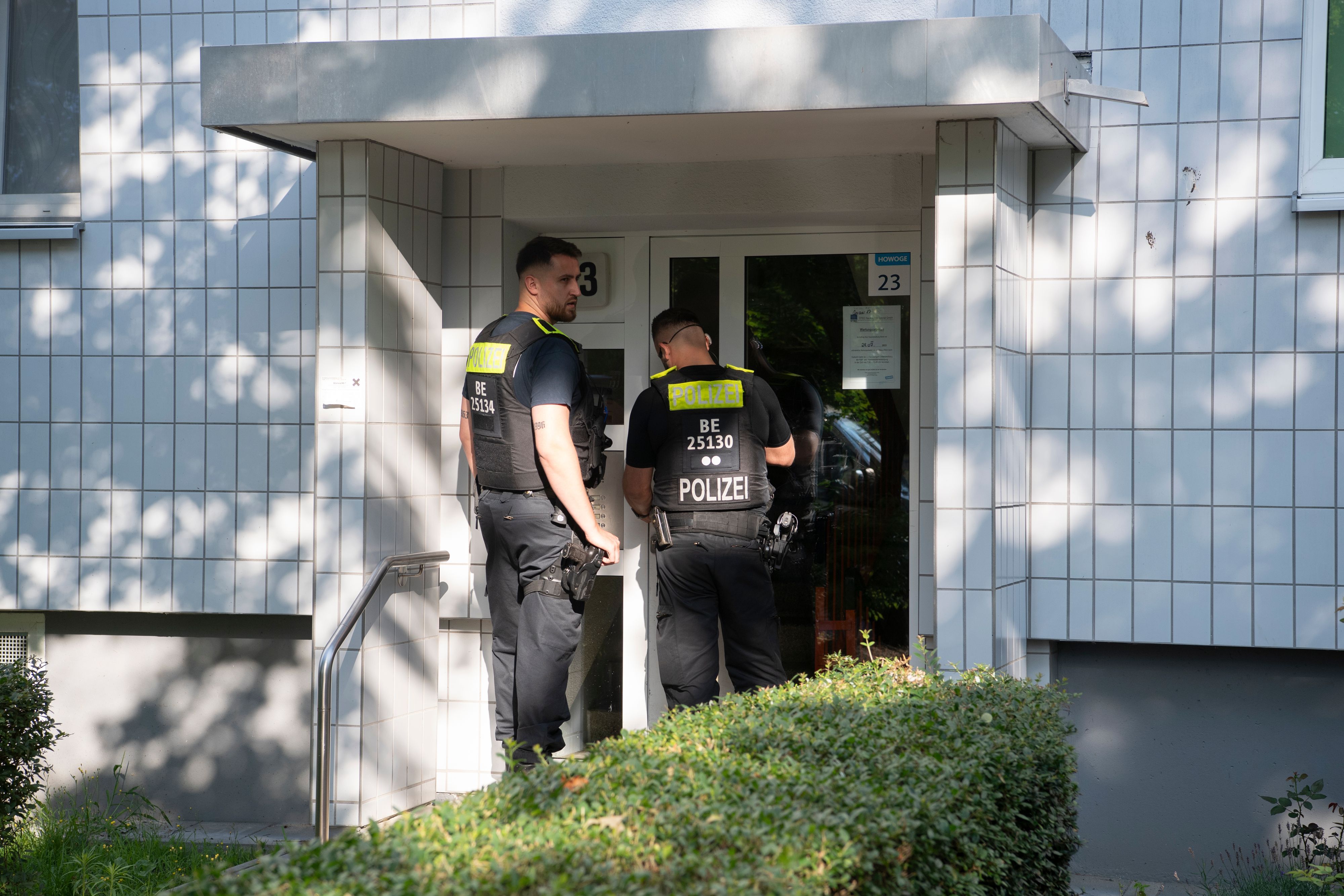 Polizeibeamte stehen vor einer Haustür.