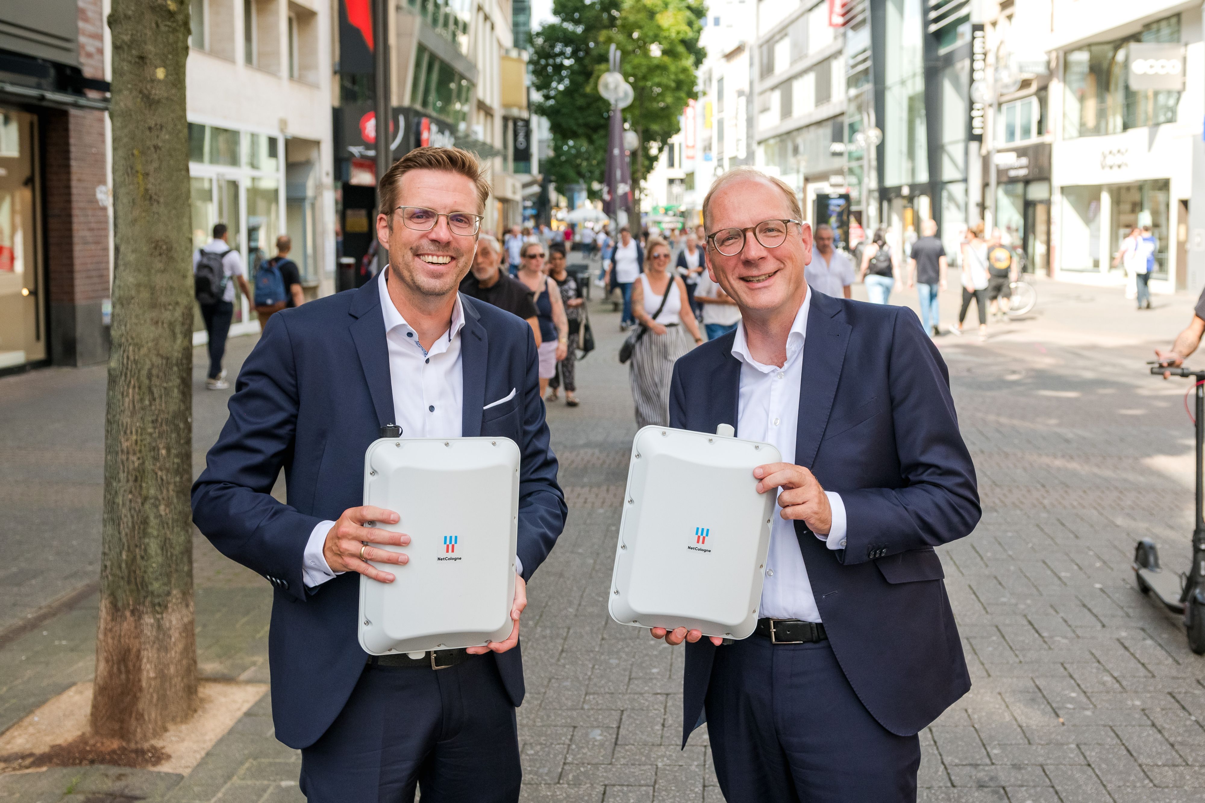 Zwei Männer stehen mit Routern auf der Schildergasse in Köln.
