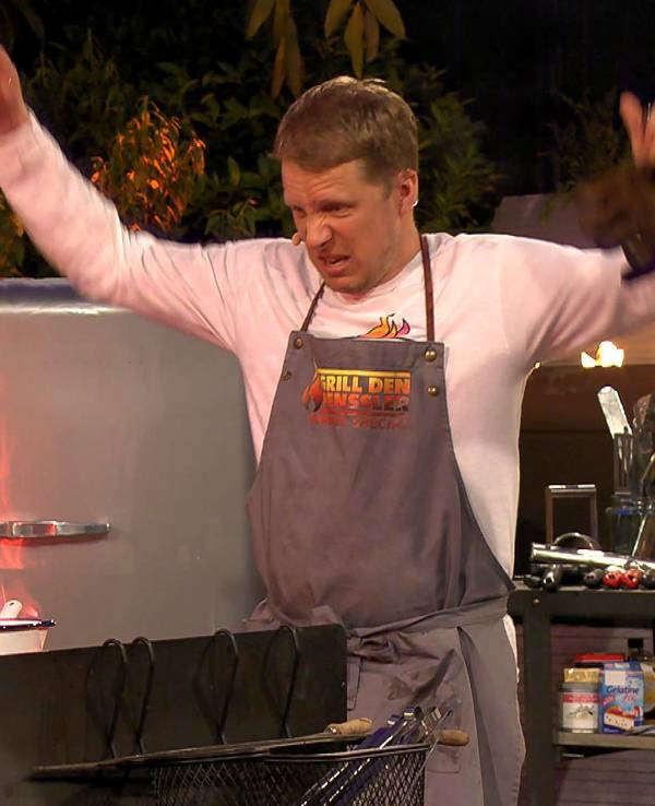 Oliver Pocher steht bei „Grill den Henssler“ vor einer lodernden Flamme in der Küche.