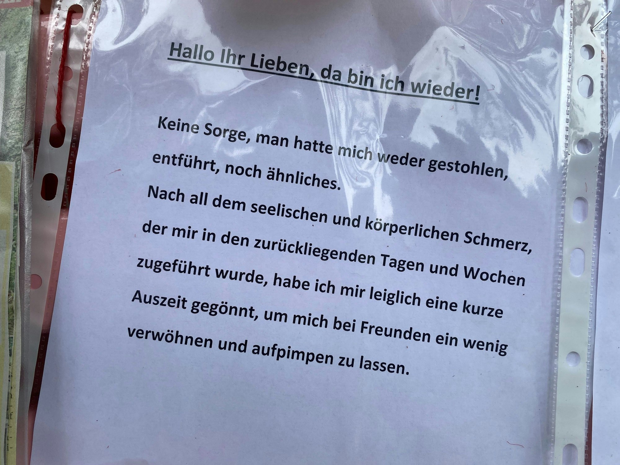 Ein Zettel in einer Klarsichtfolie hängt an der Bank von Dirk Bachs Grab.