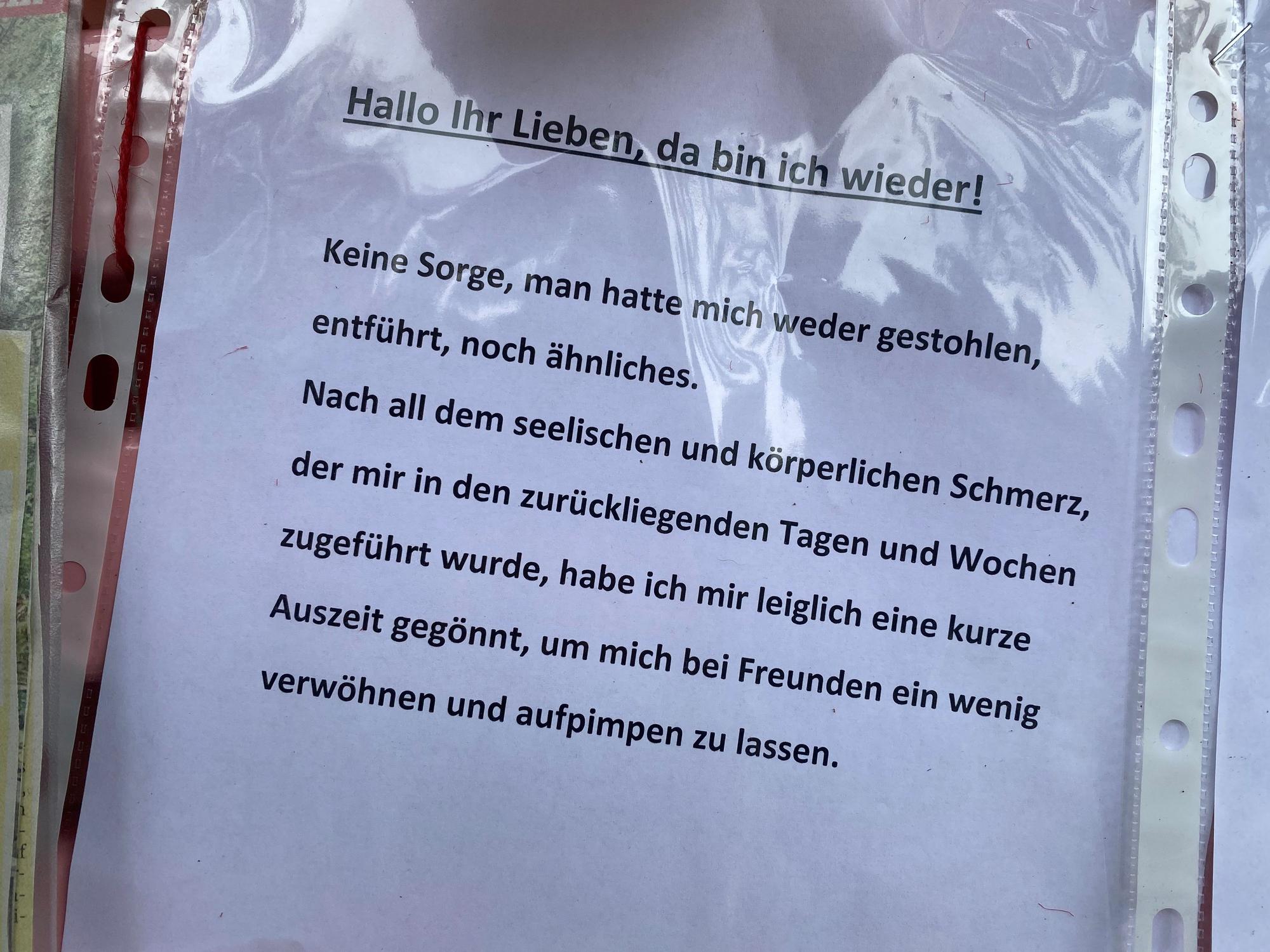 Ein Zettel in einer Klarsichtfolie hängt an der Bank von Dirk Bachs Grab.