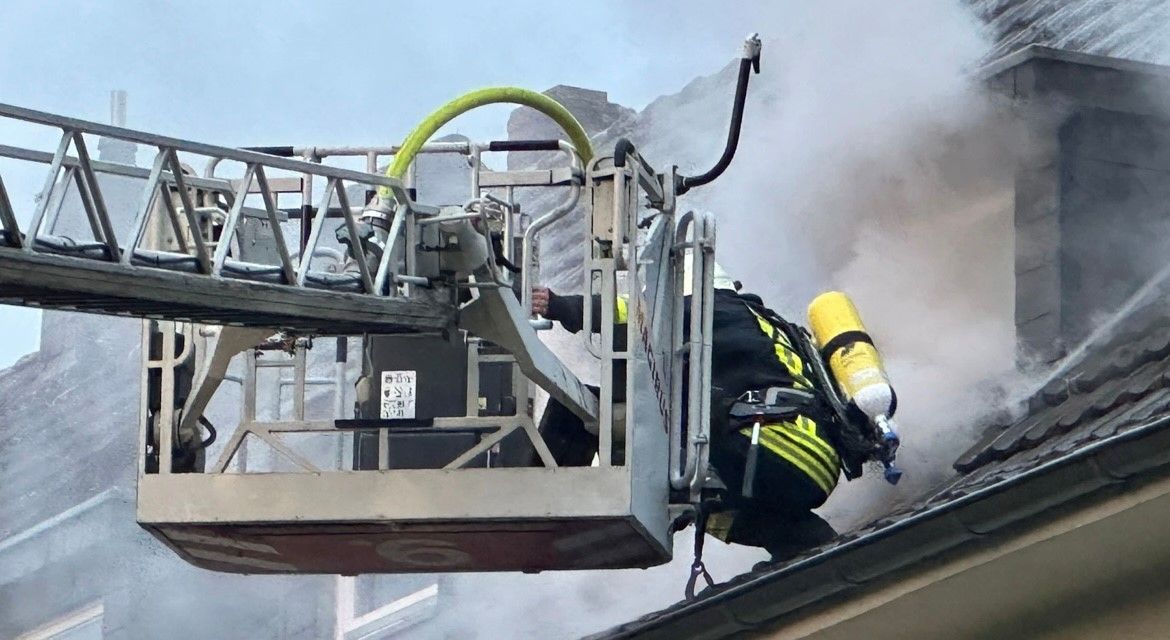 Feuerwehr auf dem brennenden Dach eines Mehrfamilienhauses in Dünnwald
