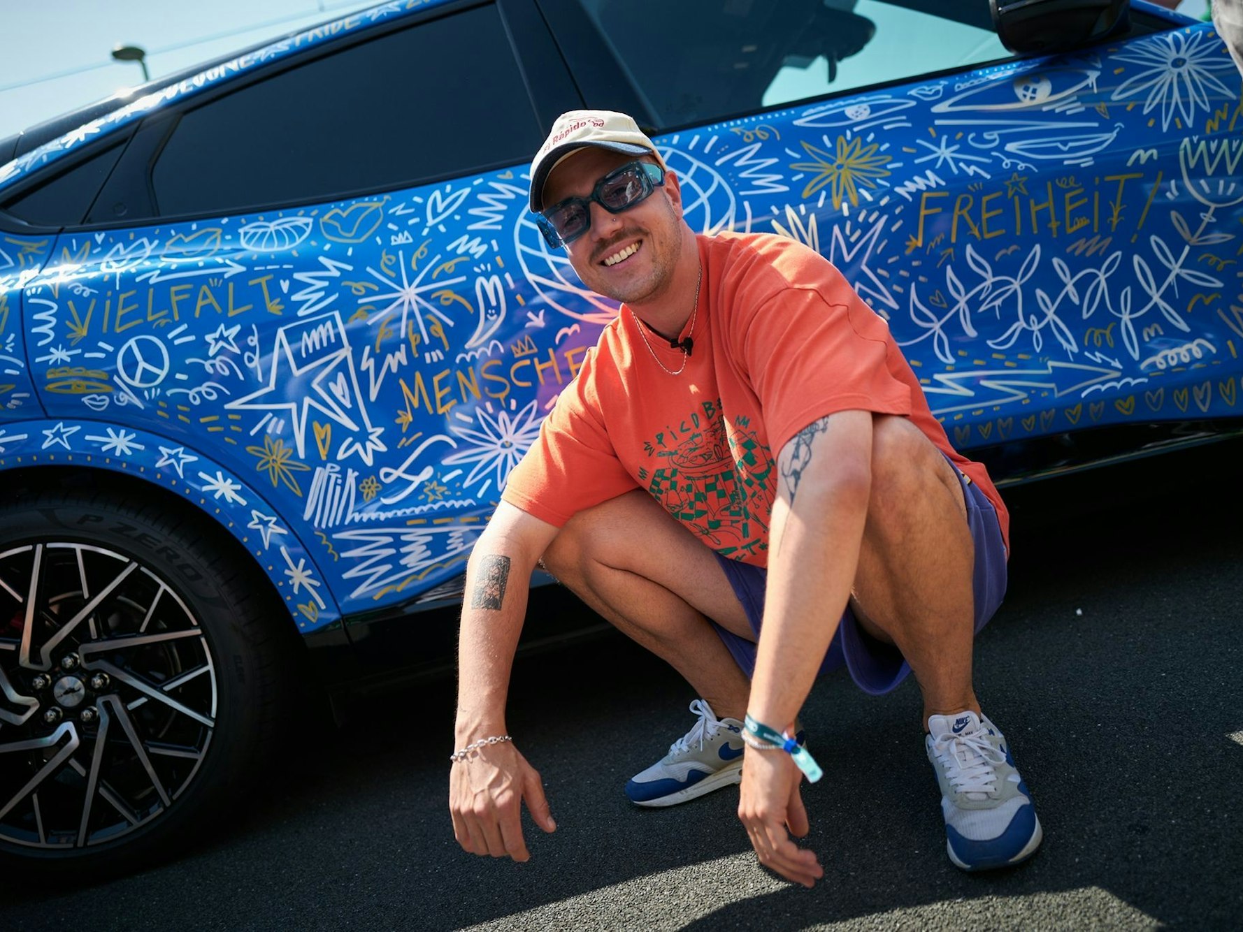 Jakob Schwald vor einem Auto, dass er für den CSD bemalen durfte.