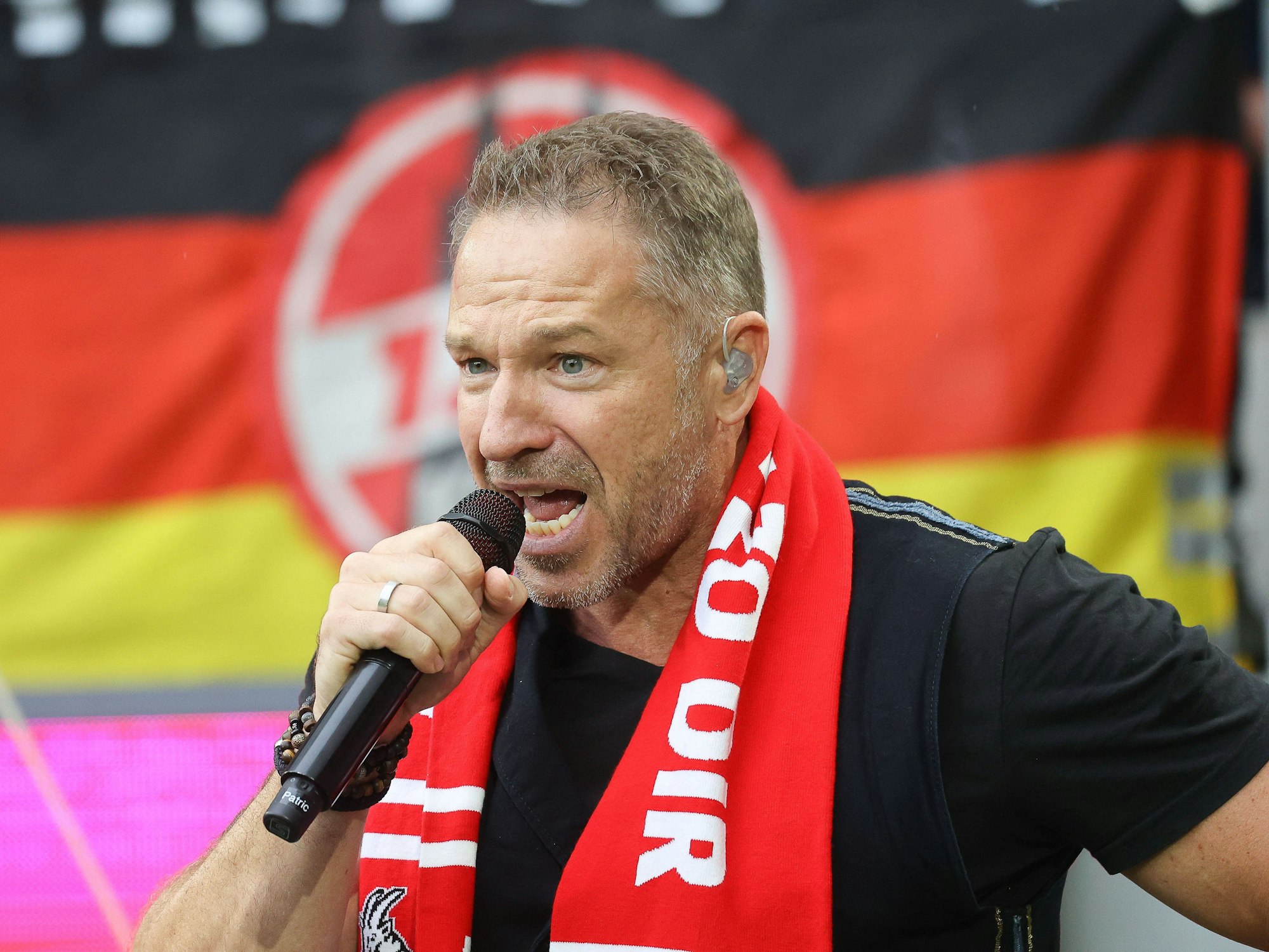Patrick Lück hält ein Mikrofon in der Hand und singt.