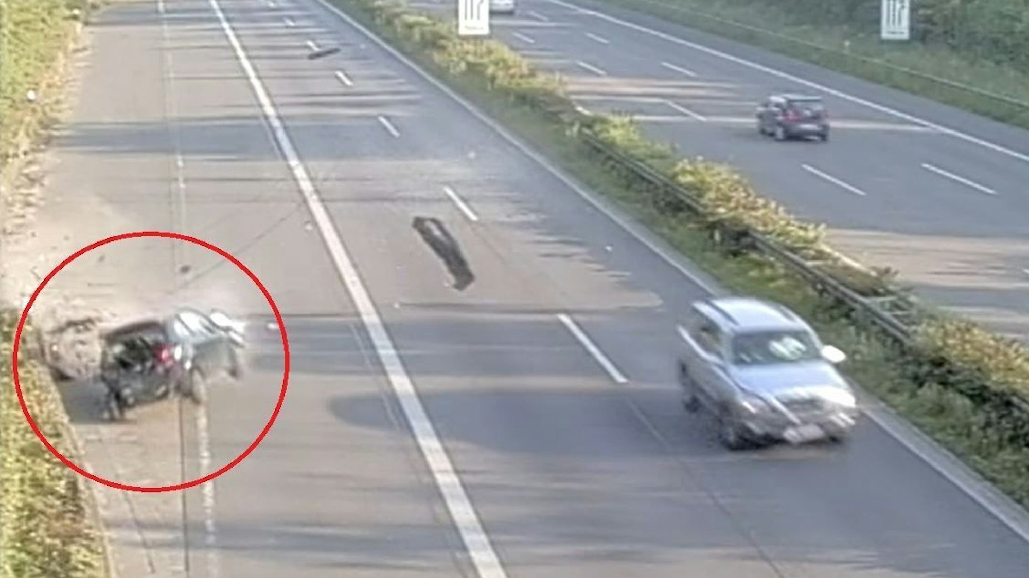 Screenshot aus einem Überwachungsvideo von der A57 in Köln. Gerade kracht ein schwarzes Auto in eine Begrenzungsmauer.