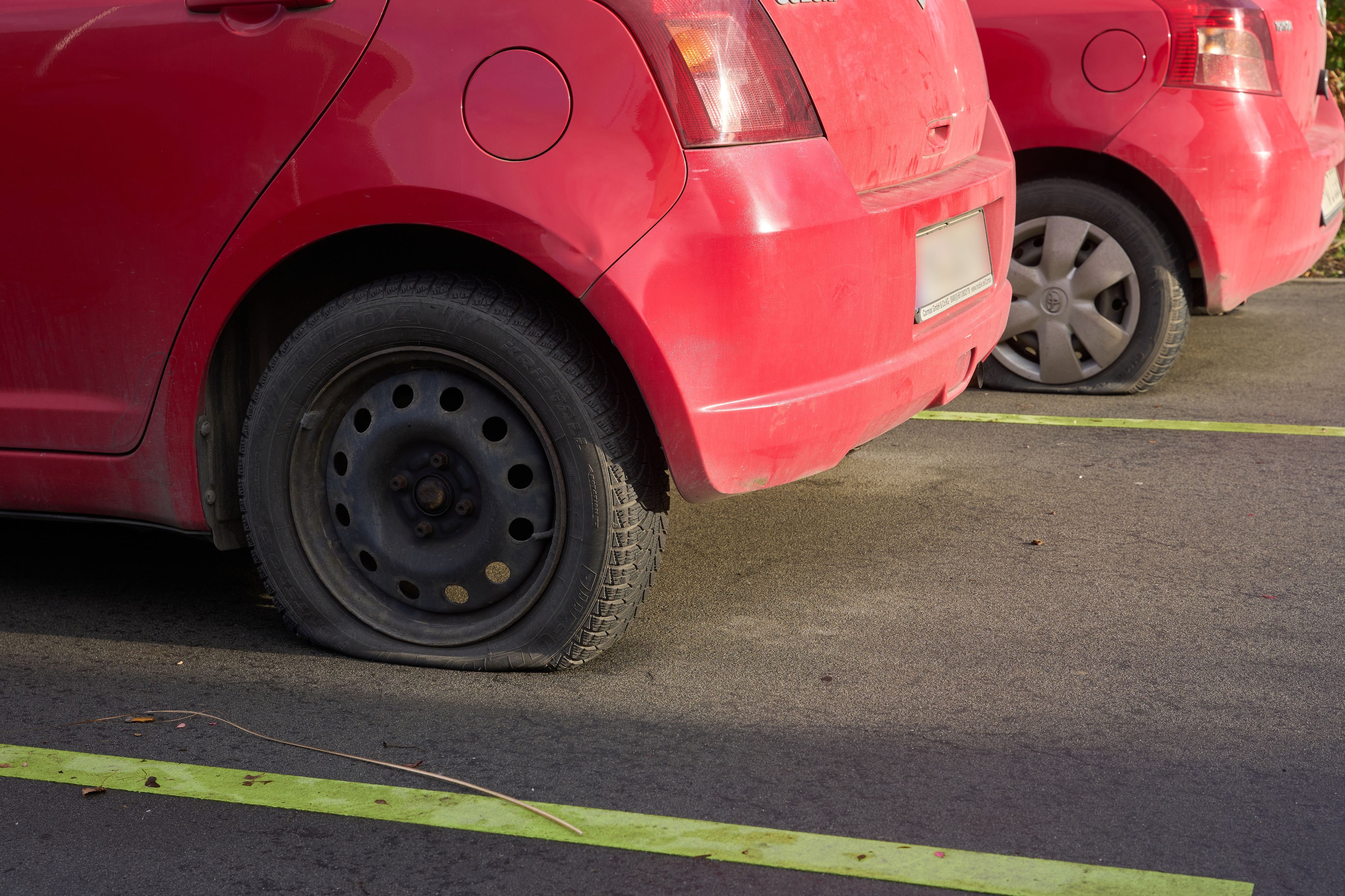 Autos mit platten Reifen stehen stehen auf einem Parkplatz.