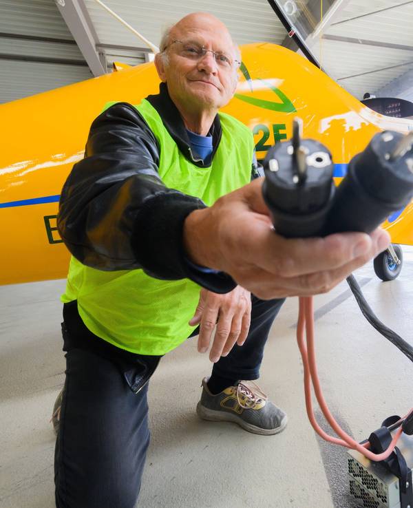 Testpilot Uwe Nortmann zeigt einen Spannungswandler vor dem E-Flugzeug „Elektra Trainer“ am Flughafen Hannover, hier im August 2023.