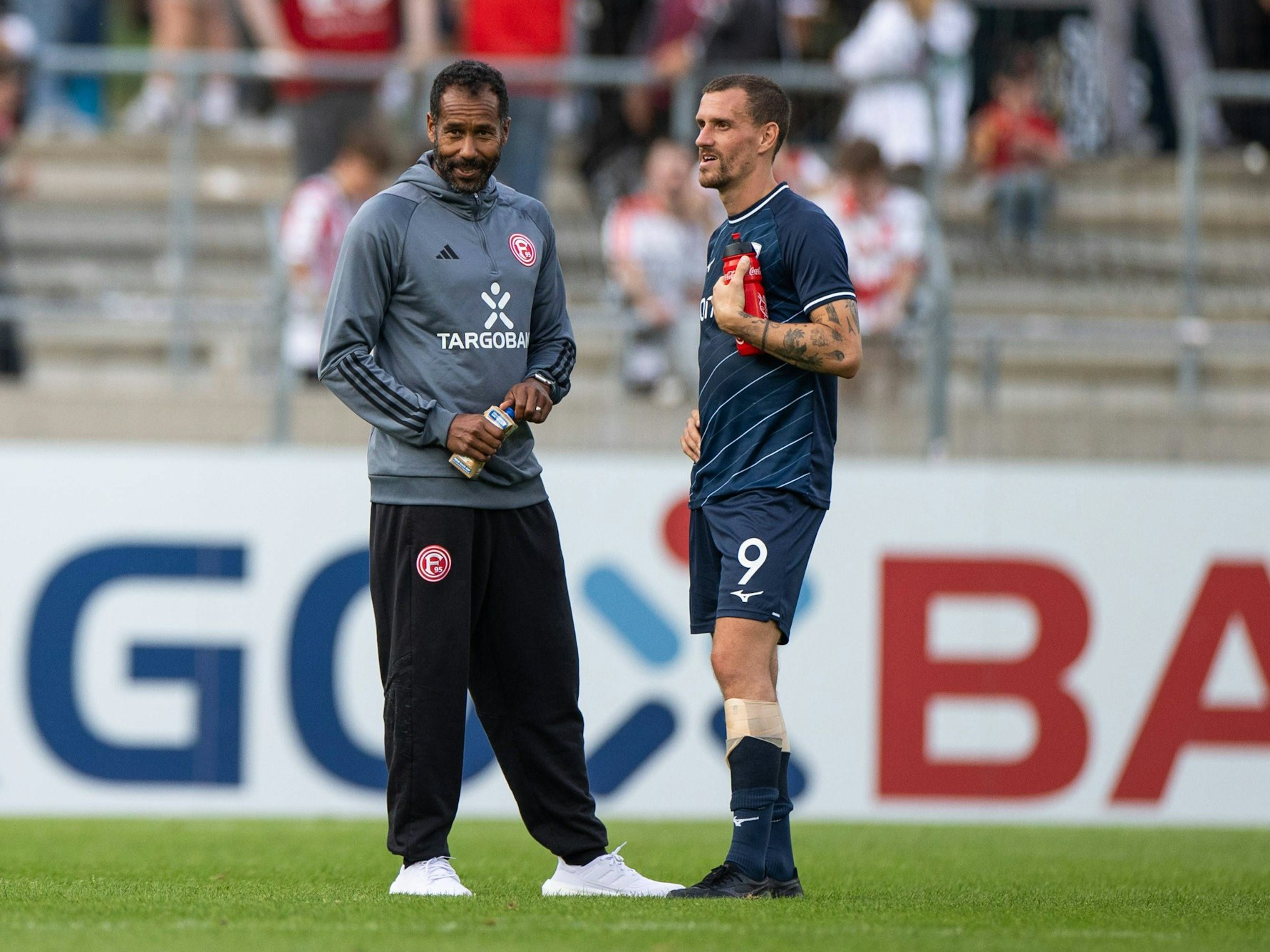 Fortuna Düsseldorfs Trainer Daniel Thioune und Bochums Stürmer Simon Zoller unterhalten sich auf dem Platz.