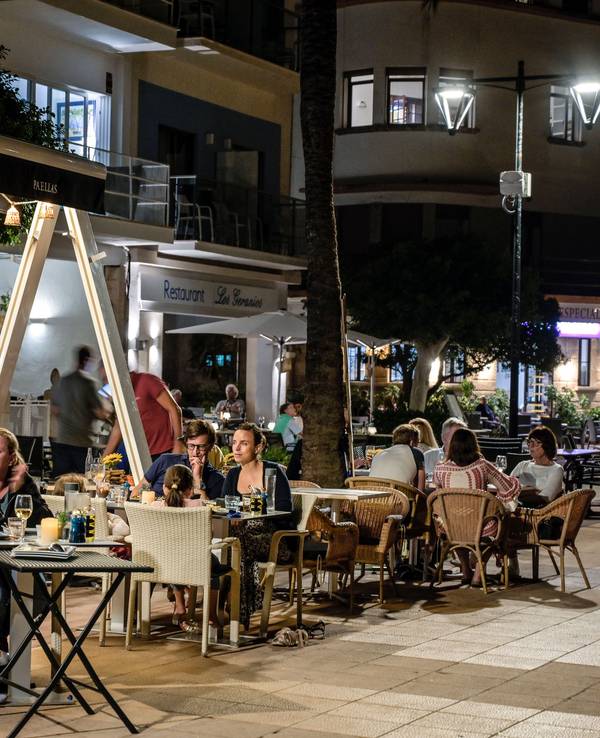 Menschen sitzen in Restaurants an der Strandpromenade von Port de Soller auf Mallorca.