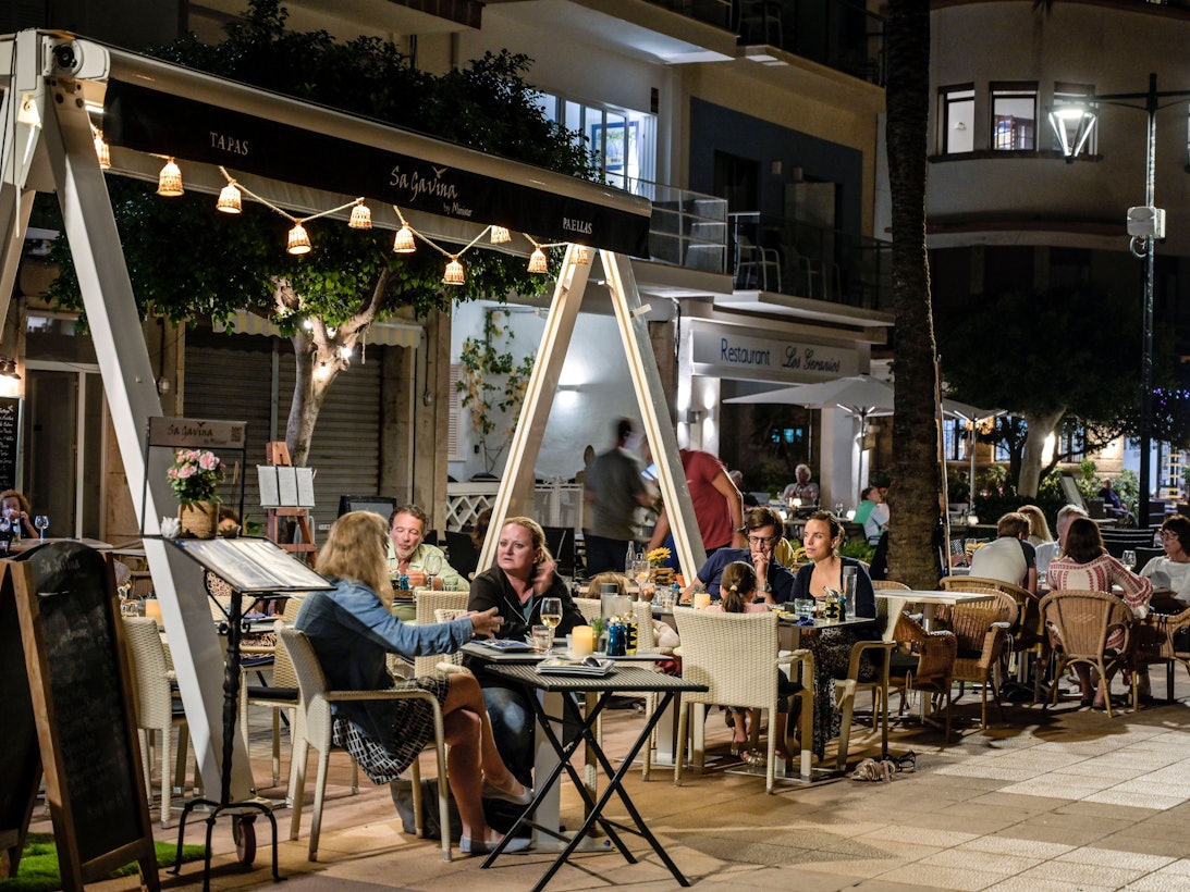 Menschen sitzen in Restaurants an der Strandpromenade von Port de Soller auf Mallorca.