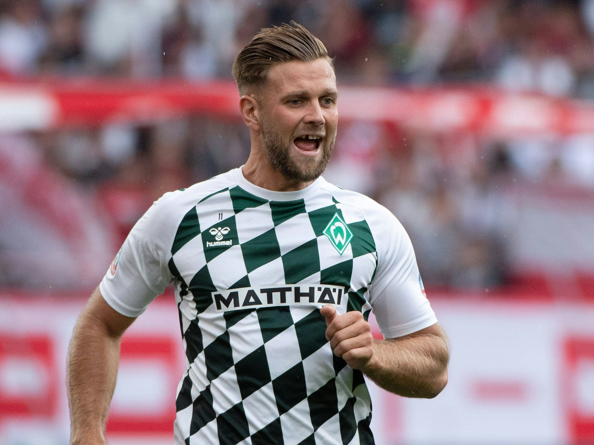 Niclas Füllkrug jubelt und öffnet dabei seinen Mund. Zu sehen: Seine Zahlücke.