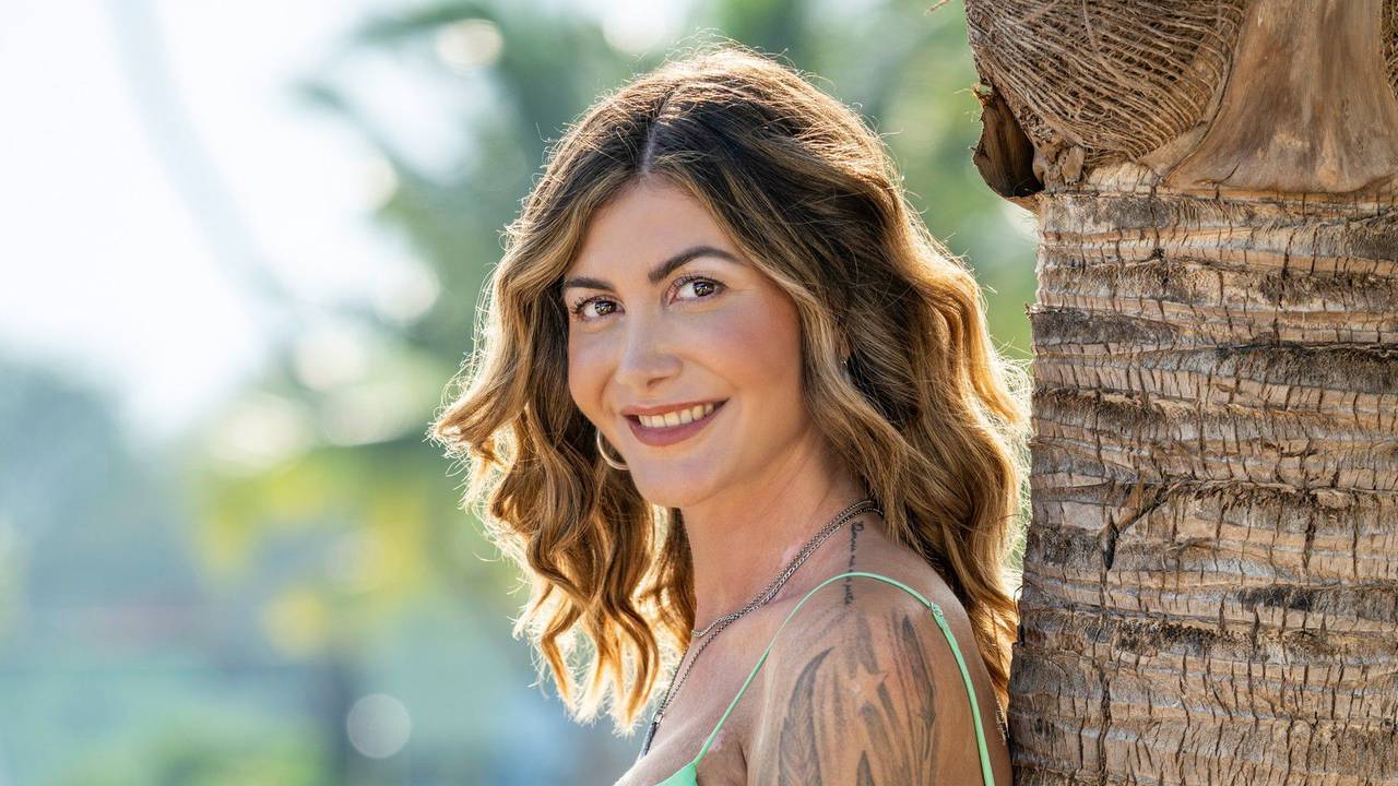 Stephie Stark lehnt sich an eine Palme.