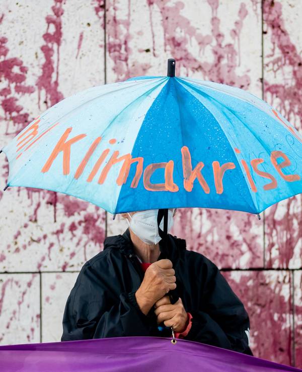 Ein Demo-Teilnehmer hält einen Regenschirm mit der Aufschrift „Klimakrise“.