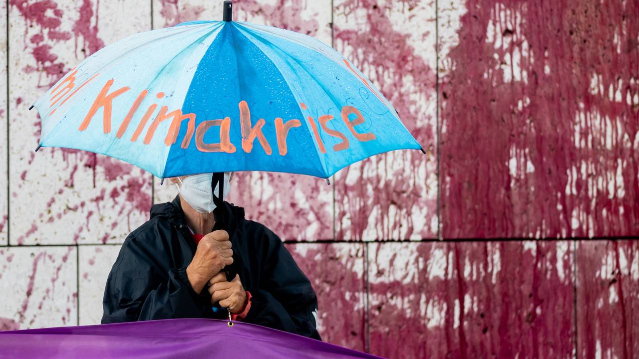 Ein Demo-Teilnehmer hält einen Regenschirm mit der Aufschrift „Klimakrise“.