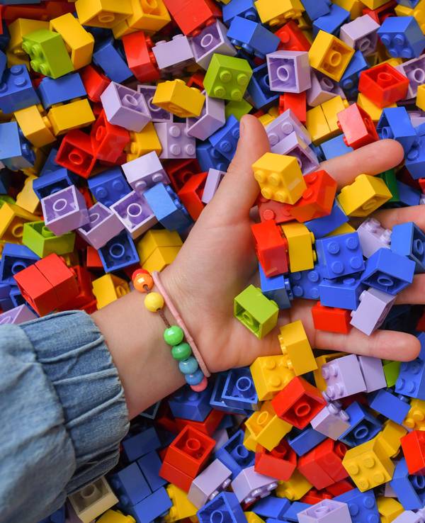 Ein Mädchen greift in eine Kiste voller Lego-Steine.