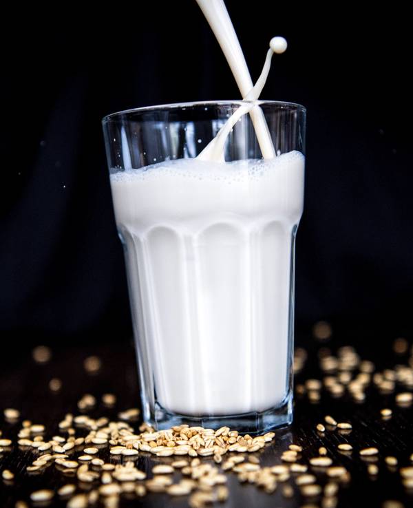 Hafermilch wird in ein Glas geschüttet.