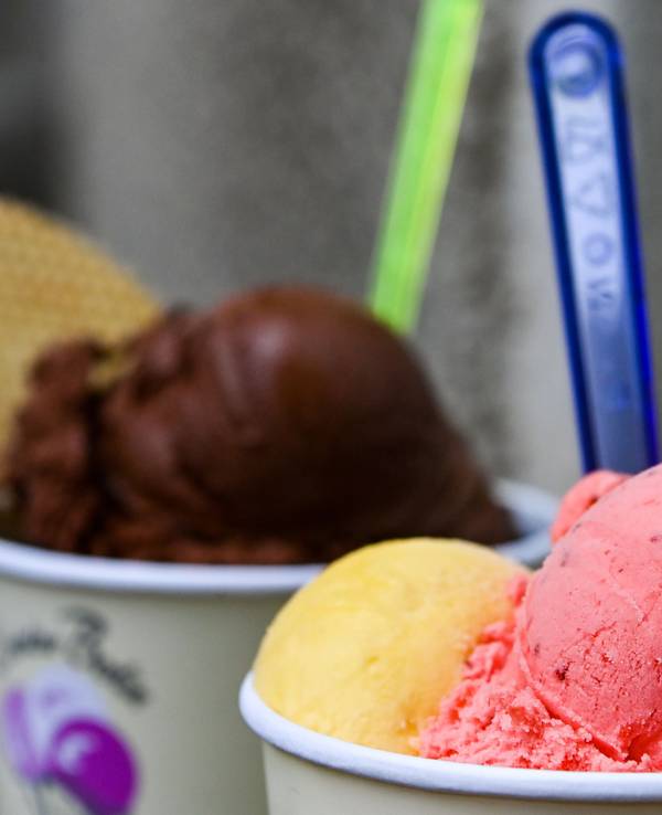 Eisbecher mit Kugeln verschiedener Sorten Eis stehen auf einem Tisch in einer Eisdiele.