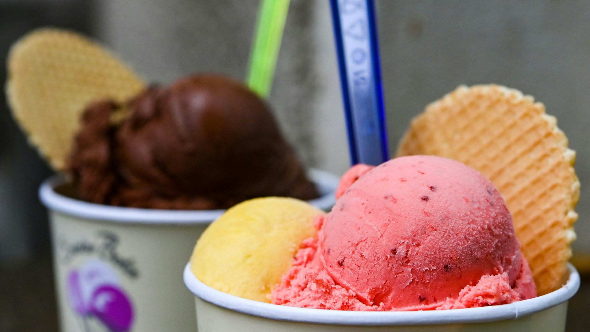 Eisbecher mit Kugeln verschiedener Sorten Eis stehen auf einem Tisch in einer Eisdiele.