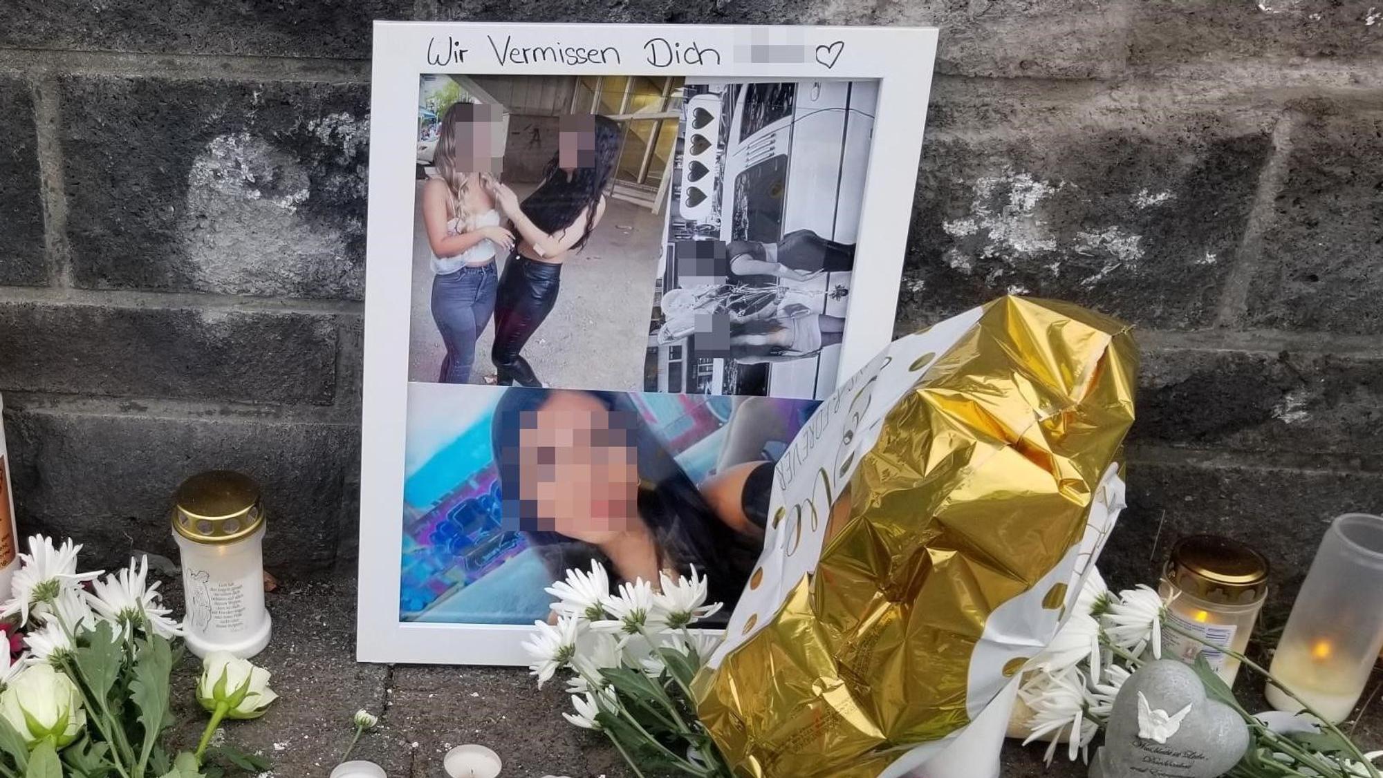 Fotos von Matilda sind an eine Mauer gelehnt, davor stehen Kerzen und liegen Blumen.