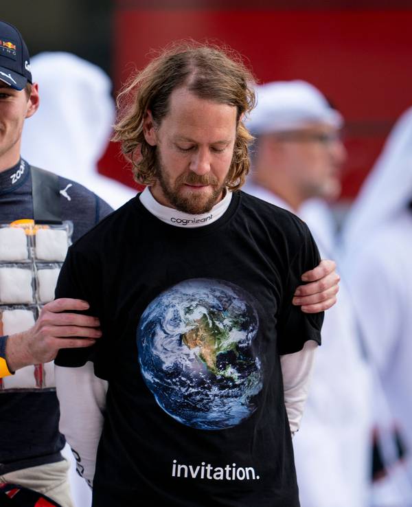Sebastian Vettel aus Deutschland vom Team Aston Martin trägt beim Großen Preis von Abu Dhabi ein schwarzes T-Shirt über mit Weltkugel darauf und der Aufschrift «invitation» (Einladung), links daneben Max Verstappen aus den Niederlanden vom Team Oracle Red Bull.