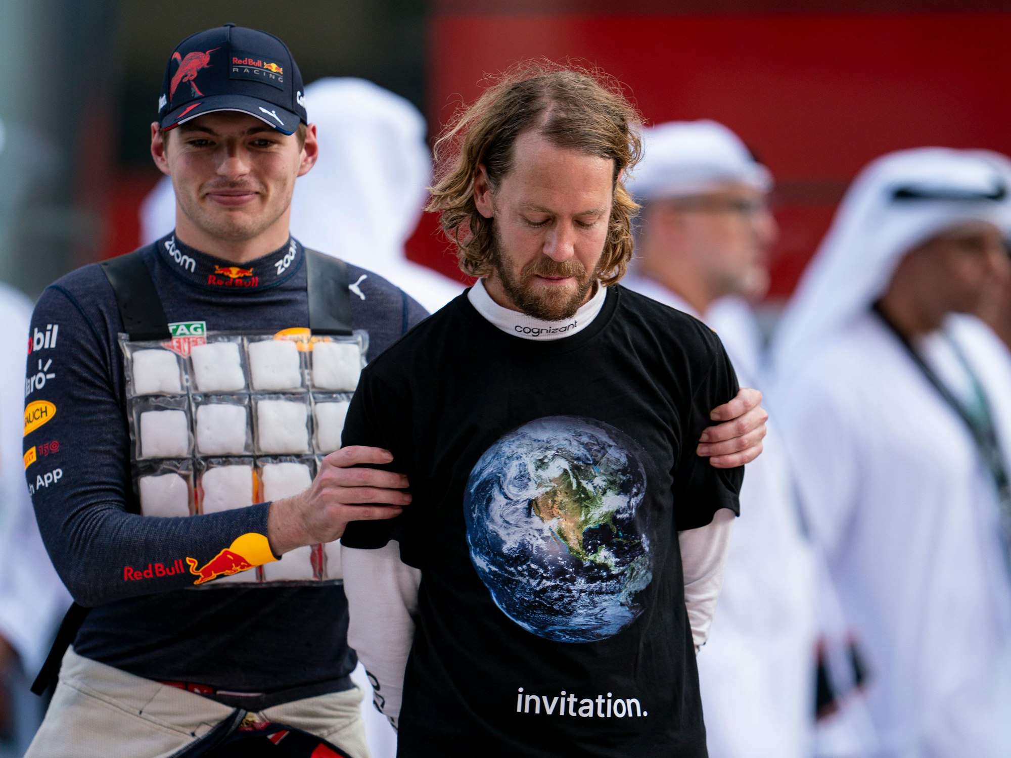 Sebastian Vettel aus Deutschland vom Team Aston Martin trägt beim Großen Preis von Abu Dhabi ein schwarzes T-Shirt über mit Weltkugel darauf und der Aufschrift «invitation» (Einladung), links daneben Max Verstappen aus den Niederlanden vom Team Oracle Red Bull.