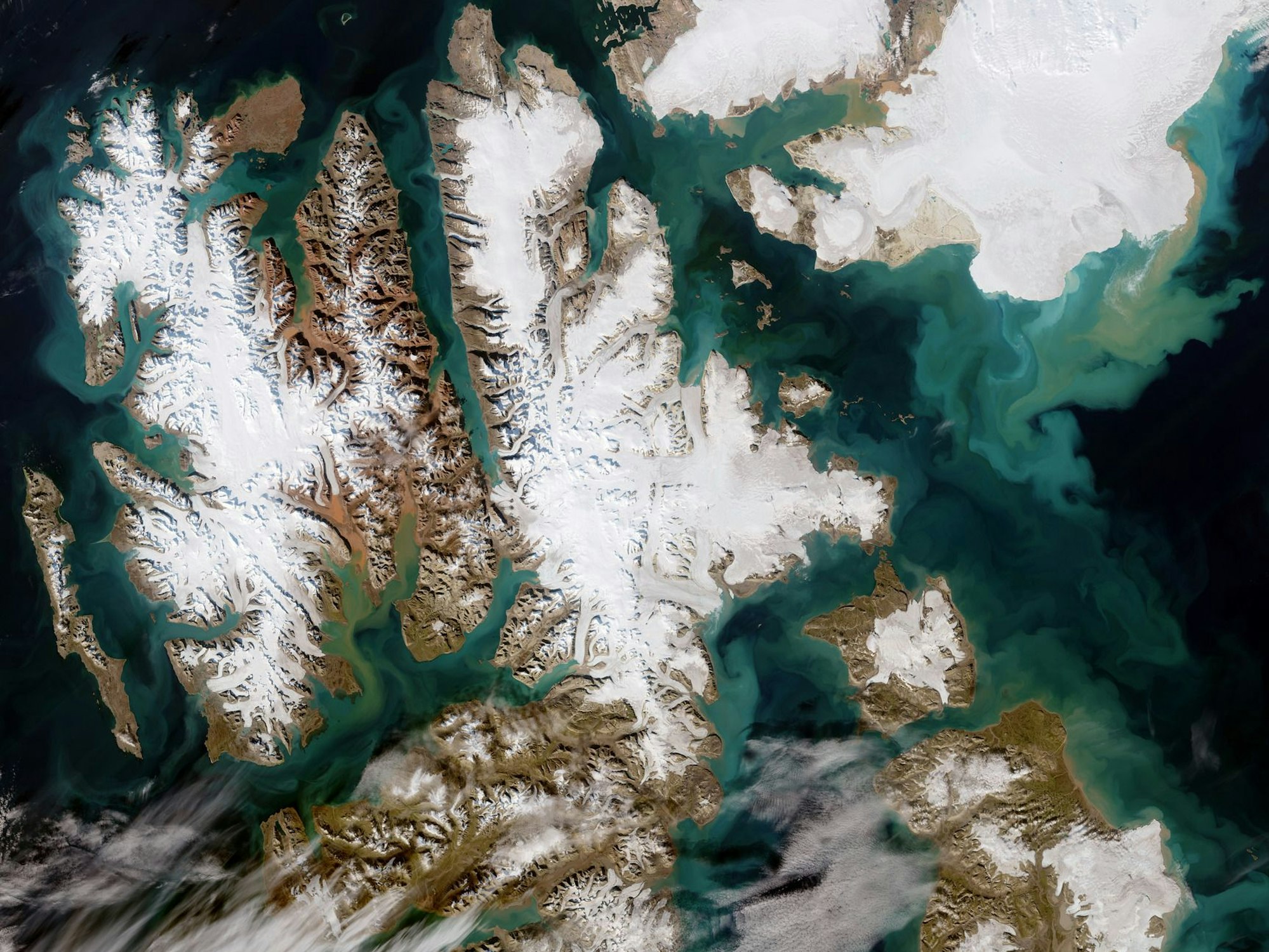 Die von der Europäischen Weltraumorganisation Esa mit modifizierten Copernicus-Sentinel-Daten (2022) verarbeitete Satellitenaufnahme zeigt die ungewöhnlich wolkenfreie Inselgruppe Svalbard: Die größte ist Spitzbergen (l.), gefolgt von Nordaustlandet (oben r.) und Edgeøya (unten r.). An einigen Orten auf Svalbard riecht es aktuell nach Schwefel.