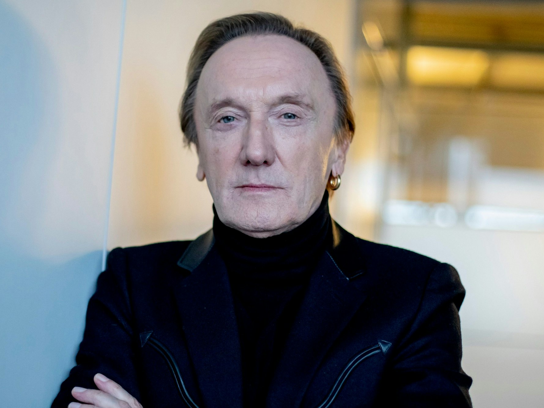 Marius Müller-Westernhagen lehnt an einer Wand und schaut entspannt in die Kamera.