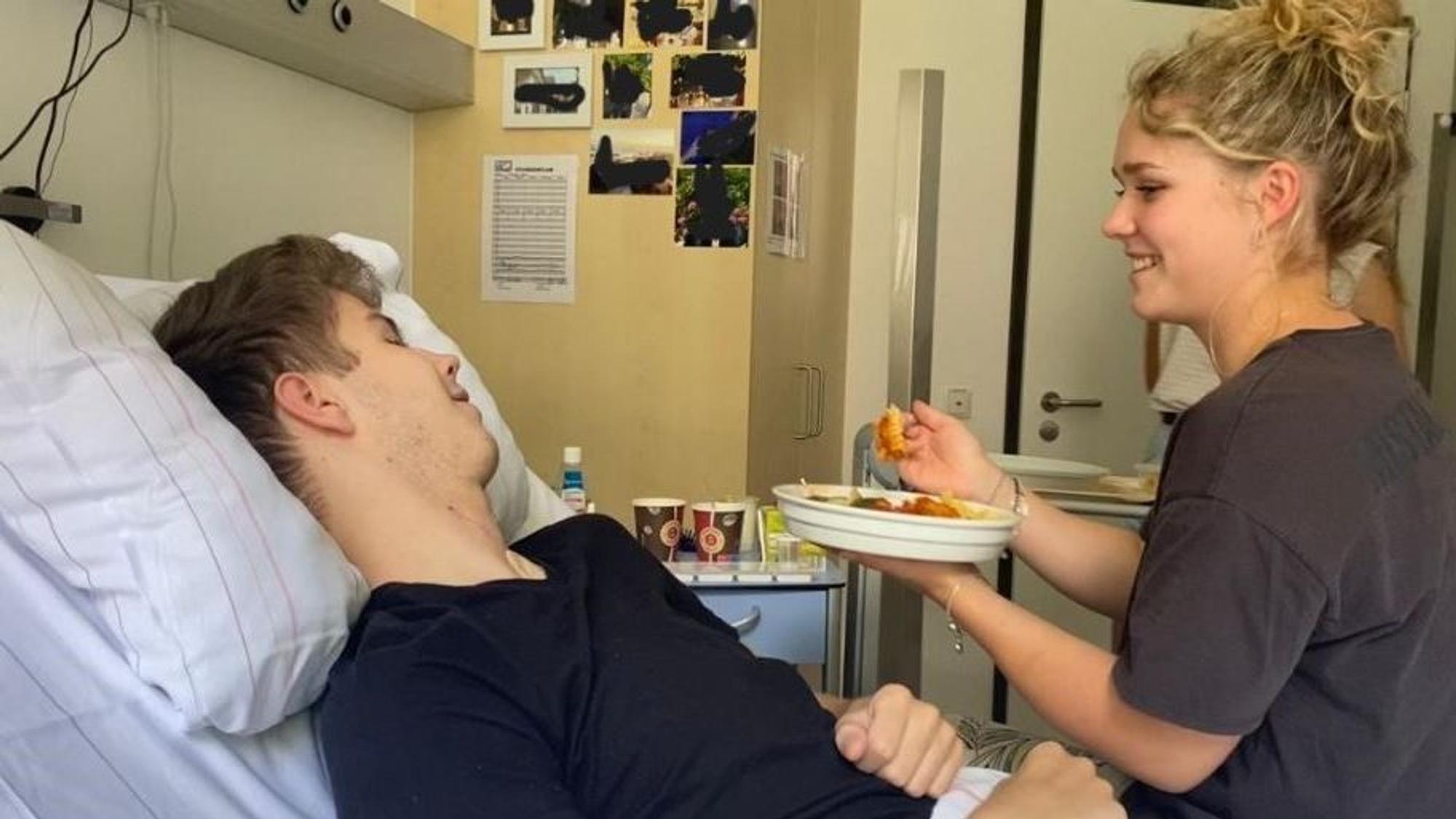 Eine junge Frau hilft einem gelähmten Mann beim Essen.
