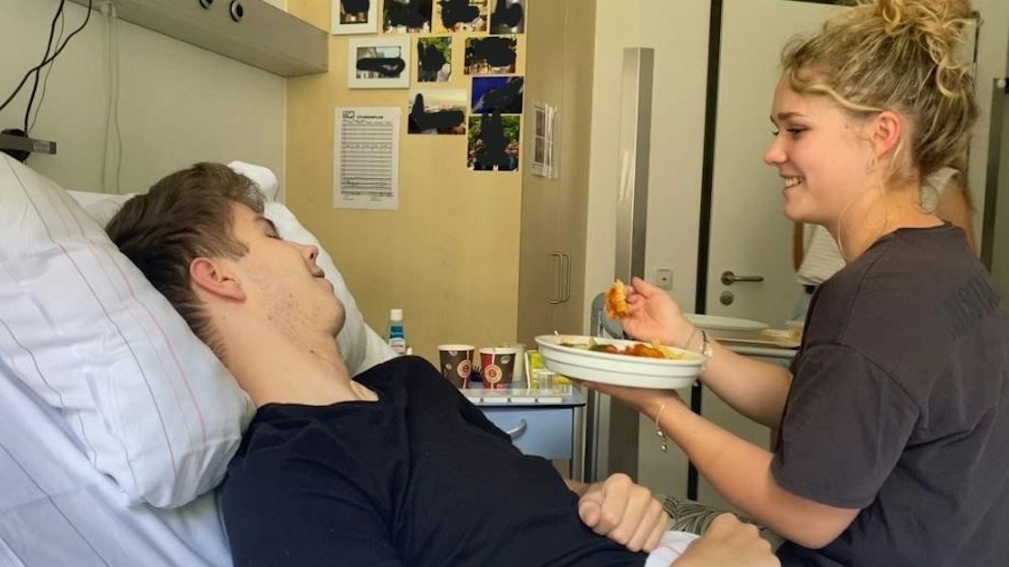 Eine junge Frau hilft einem gelähmten Mann beim Essen.