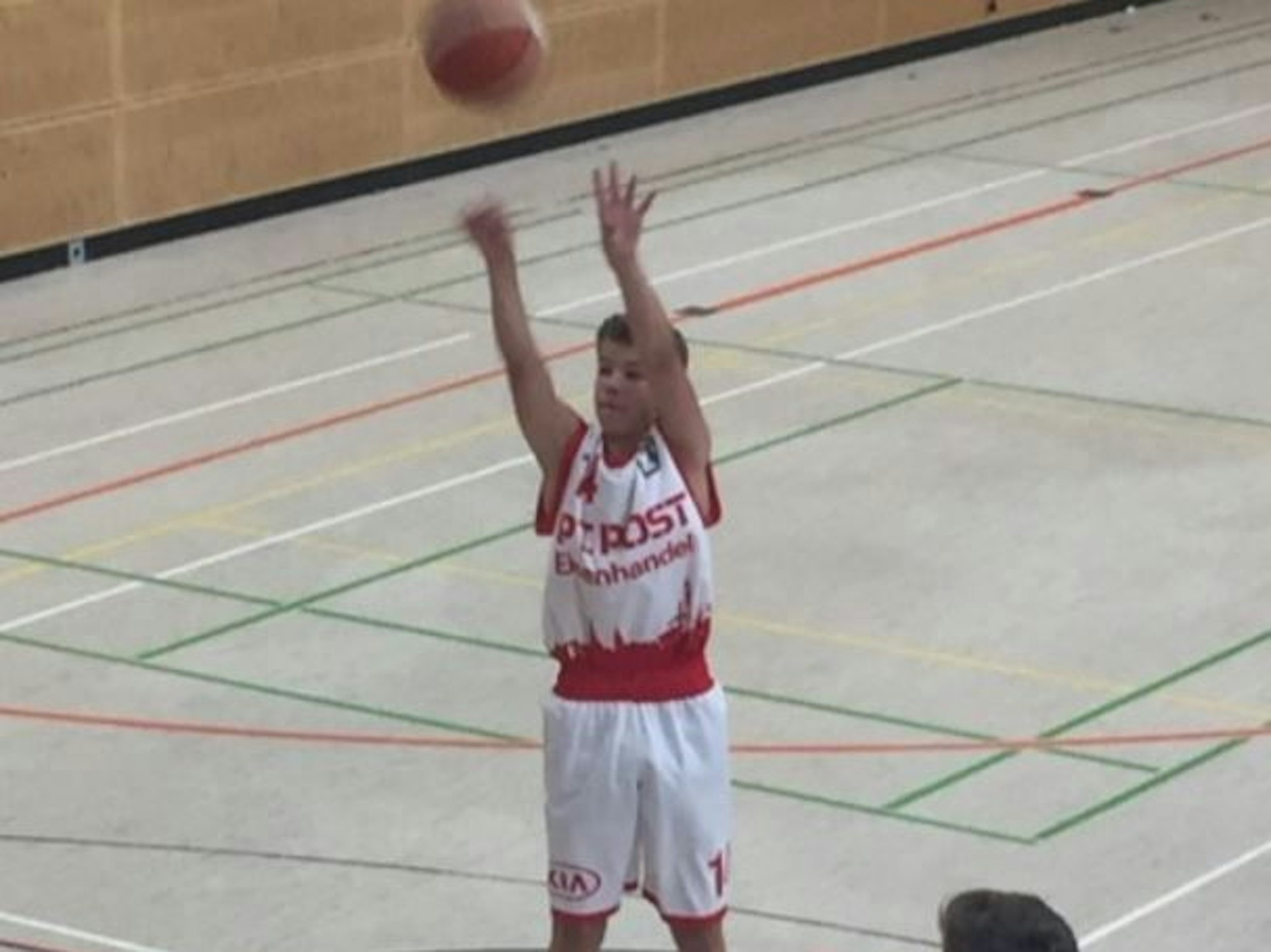 Ein Jugendlicher wirft beim Basketball einen Ball in Richtung Korb.