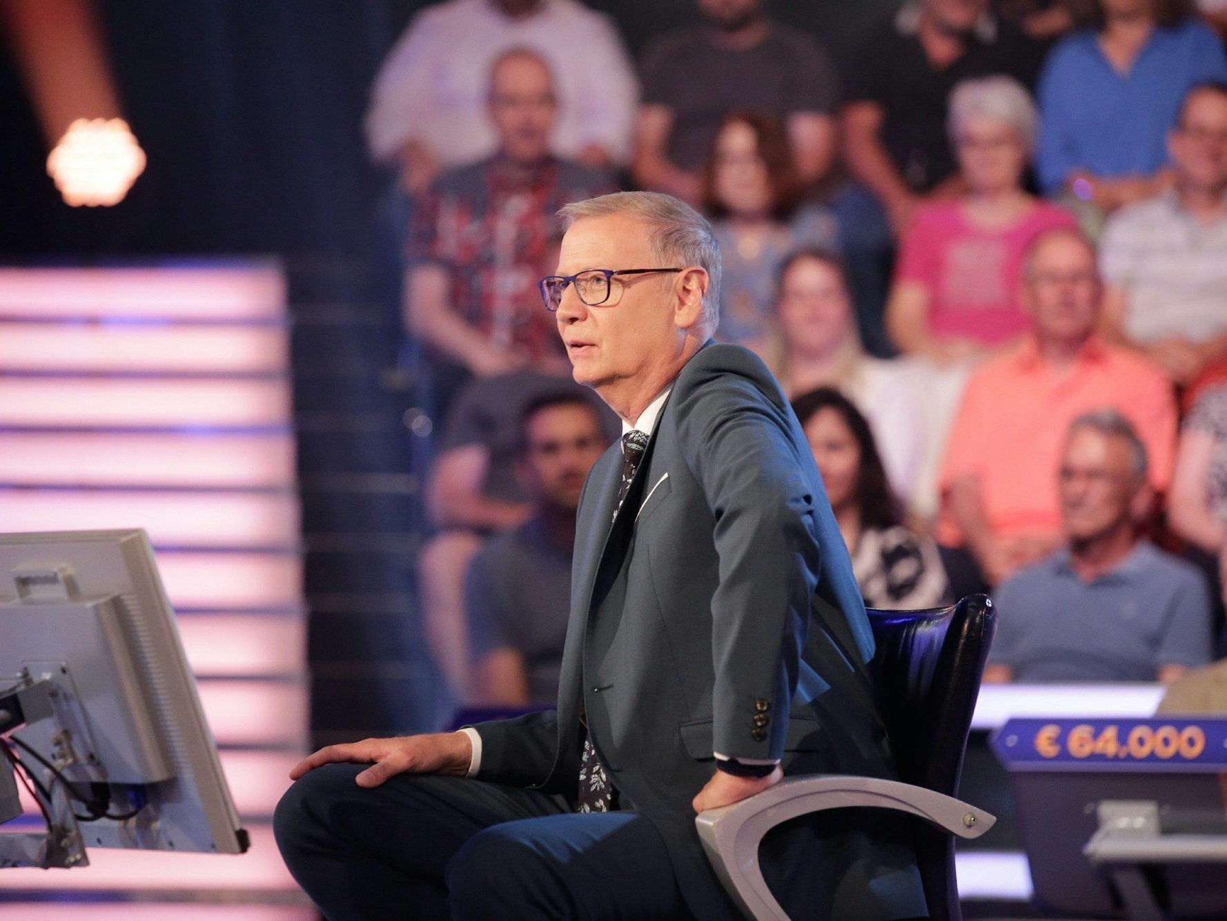 Moderator Günther Jauch sitzt auf einem Stuhl.