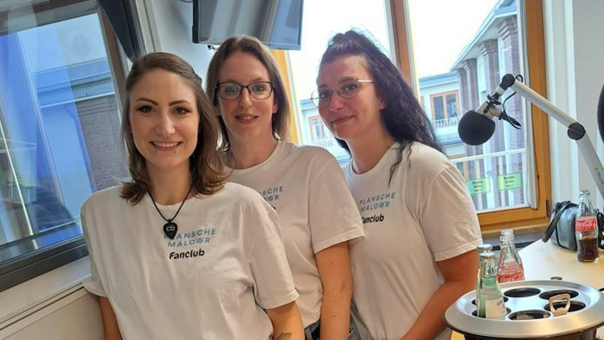 Drei Frauen stehen in einem Tonstudio und grinsen in die Kamera.