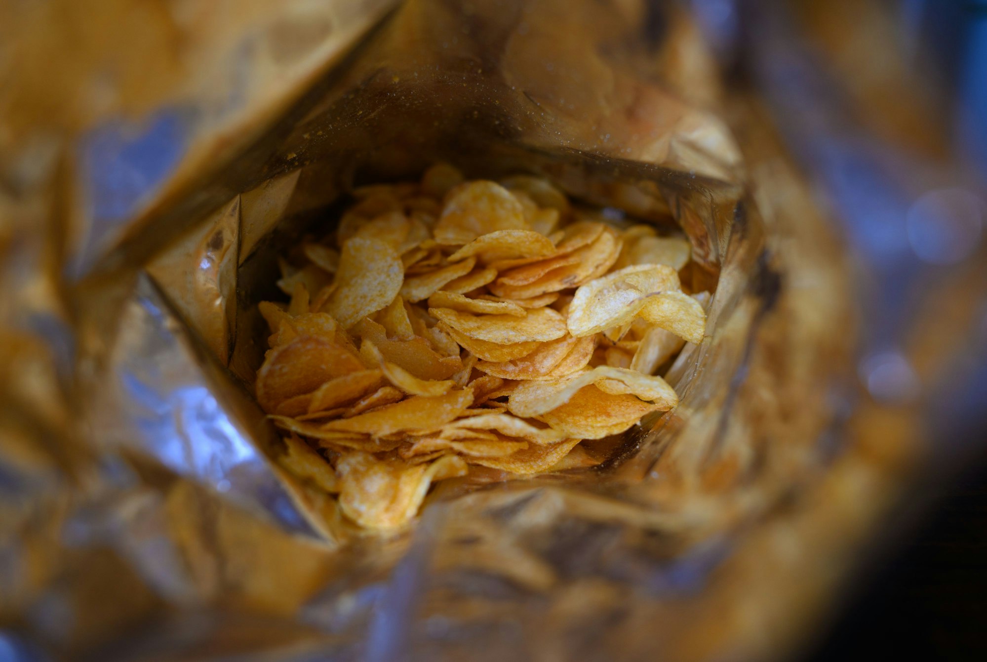Eine offene Tüte Kartoffelchips liegt auf einem Tisch.